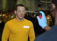 110218-N-SO729-185 GULF OF THAILAND (Feb. 18, 2011) - Information Technician Seaman Cody Clay gets sprayed with oleoresin capsicum spray during a security qualification course in the hangar bay of the forward-deployed amphibious assault ship USS Essex (LHD 2).