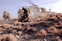 U.S. Special Operations personnel take cover to avoid flying debris as they prepare to board a UH-60 Black Hawk helicopter during a mission in Kunar province, Afghanistan, Feb. 25, 2012.