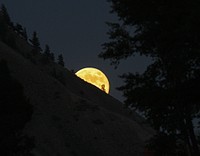 Yellow moon peeking out from mountain. Original public domain image from Flickr