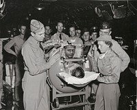 Iron lung patient, Robert Vande Zande, AK3, formerly stationed with Fasron 117 at Barbers Point is being briefed by Doctor Isham (Captain, Medical Corps) U.S. Army of Tripler Army Hospital and Ensign Virginia Pluke (Nurse Corps) U.S. Navy of the 1453 Medical Air Evacuation Squadron prior to take off for the Great Lakes Naval Hospital.