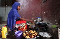 A young woman cooks samosas on a small stove at a market in Mogadishu, Somalia, during the holy month of Ramadan on July 11. AU UN IST PHOTO / ILYAS A. ABUKAR. Original public domain image from <a href="https://www.flickr.com/photos/au_unistphotostream/9268731784/" target="_blank" rel="noopener noreferrer nofollow">Flickr</a>