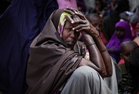 A woman waits in the shade of a derelict building to see a doctor at a free medical clinic provided by the Kenyan Contingent serving with the African Union Mission in Somalia (AMISOM) in the southern Somali port city of Kismayo, 19 August 2013.