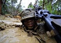 U.S. Navy Construction Electrician 2nd Class Dwayne Watson uses his weapon to push razor wire away from his face during an endurance course Sept. 22, 2013, at the Marine Corps Jungle Warfare Training Center at Camp Gonslaves, Japan.