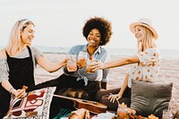 Friends clinking their glasses at a beach party, warm tone