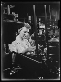 Production. Machine guns of various calibers. A drilling operation on the pawl pin of a machine gun in a large Eastern plant. This girl operator is one of many women making a direct contribution to the all-important job of keeping our men in the field well armed for the task ahead. Sourced from the Library of Congress.