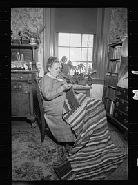 Homewoven dress and rug, Westmoreland Homesteads, Mount Pleasant, Westmoreland County, Pennsylvania. Westmoreland homesteader wearing dress of cloth woven herself on homestead looms and working on rug woven by her homestead loom. Sourced from the Library of Congress.