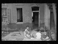 Slum front yard playground, Washington, D.C. Such is the front yard available to these two youngsters to play in. Sourced from the Library of Congress.
