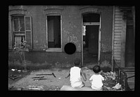 [Untitled photo, possibly related to: Slum front yard playground, Washington, D.C. Such is the front yard available to these two youngsters to play in]. Sourced from the Library of Congress.