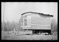 [Untitled photo, possibly related to: This one-room hut built of rough lumber over the chassis of an abandoned Ford truck was the housing provided by a landlord for an illiterate wood-cutter, with a wife and seven children. Found on U.S. Route 70 between Camden and Bruceton, Tennessee, near Tennessee River.  Family of nine lived and slept in this shack]. Sourced from the Library of Congress.