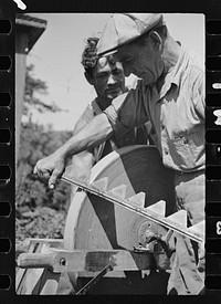 [Untitled photo, possibly related to: Sharpening knife of old mowing machine on farm near Hyde Park, Vermont]. Sourced from the Library of Congress.