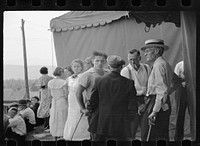 The county sheriff in "cahoots" with the carnival clown, talking a victim of $16.00 loss into a considerable reduction, "back of the tent" at the Morrisville, Vermont annual fair. Sourced from the Library of Congress.