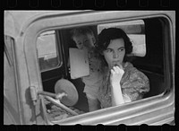 Farm wife waiting in the car while her husband attends the auction. Oskaloosa, Kansas. Sourced from the Library of Congress.