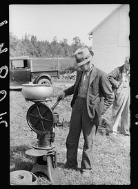 Farmer examining cream separator. Auction near Tenstrike, Minnesota. Sourced from the Library of Congress.