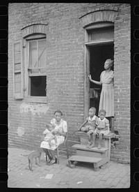[Untitled photo, possibly related to:  family in front of their alley dwelling. The older woman is a cleaning woman in the U.S. government. Washington, D.C.]. Sourced from the Library of Congress.