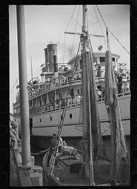 [Untitled photo, possibly related to: The economy of a town: fishing and the tourist trade. A fishing boat in front of the S.S. "Romance," a tourist boat which used to ply between Boston and Provincetown and has since sunk in Boston Harbor. Provincetown, Massachusetts]. Sourced from the Library of Congress.