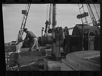 [Untitled photo, possibly related to: Aboard a trawler (locally called a dragger). The power-driven winch lets out the starboard net. While over fishing grounds one of two nets is constantly in the water, dragging along the bottom. Boats are powerful, diesel-engined, between forty and seventy-five feet long. Their unrestricted use has done much to cause the "fish-famine" along this coast because nets bring up everything, fish, minnows and even spawn. Provincetown, Massachusetts]. Sourced from the Library of Congress.