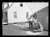 The Resettlement Administration community manager explains the operation of the sanitary underground automatic electric water pump and well to homesteader Langman. Granger, Iowa. Sourced from the Library of Congress.