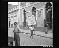 Boy carrying sign advertising a movie program. San Juan, Puerto Rico. Sourced from the Library of Congress.