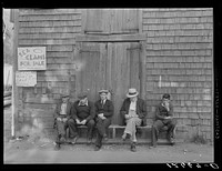 The "Sand Bar Club," a bench on the waterfront main street which is occupied all day by fishermen, unemployed fishermen and other residents with nothing to do; here they gossip, whittle, and make remarks about passing tourists. Provincetown, Massachusetts. Sourced from the Library of Congress.