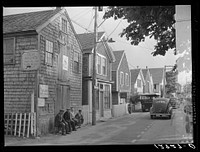 Commercial Street, the main street of Provincetown which runs along the waterfront, including a view of the "Sand Bar Club" and the tourist bus which runs out to the beach. Provincetown, Massachusetts. Sourced from the Library of Congress.