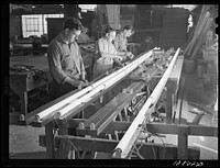 New York, New York. Preparing the defense bond sales photomural, designed by the Farm Security Administration, to be installed in the Grand Central terminal, in the shop of a contractor. Electricians wiring the flourescent lights used to illuminate the finished mural. Sourced from the Library of Congress.