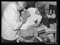 Dentist participating in FSA (Farm Security Administration) health program treats rehabilitation client. Saint Charles County, Missouri. Sourced from the Library of Congress.