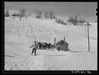 Every available space for parking is used by skiers on weekends at Clinton Gilbert's farm. The house is about eight years old; purchased by Gilbert in 1929. He has about 150 acres, mainly a dairy farm with twenty three cows. He also makes about one hundred gallons of maple syrup every year. First skiing town in U.S. built on this farm in 1934 by White Cupboard Inn, but Gilbert now owns and runs tow and it has increased his income about 25 percent. Has enabled him to build small ski lodge and do many repairs to property. Sourced from the Library of Congress.