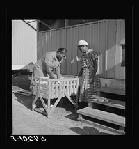 The nurse examines one of the camp's first babies. Mother and child are given both prenatal and postnatal care by nurse and doctor at clinic too. Okeechobee migratory labor camp. Belle Glade, Florida. Sourced from the Library of Congress.
