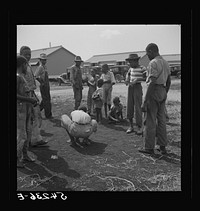 Camp members' children playing marbles outside their shelter units at Okeechobee migratory labor camp. Belle Glade, Florida. Sourced from the Library of Congress.