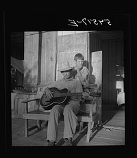 [Untitled photo, possibly related to: Farmer playing guitar on the porch in the evening. Near Natchitoches, Louisiana]. Sourced from the Library of Congress.