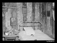 Melrose, Natchitoches Parish, Louisiana. Bedroom with religious pictures, etc. on mud walls of old hut built and still occupied by French mulattoes, near John Henry cotton plantation. Belongs to Rocque family (see general caption). Sourced from the Library of Congress.