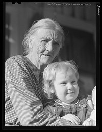 Mountain woman and grandchild sitting on the porch of their home up Frozen Creek, Breathitt County, Kentucky. Sourced from the Library of Congress.