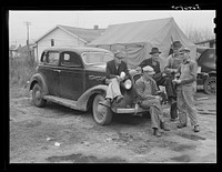 [Untitled photo, possibly related to: Men on car by tents. Construction workers in front of tents. Names: William Allen Jones, Fort Benning, Paul Knight, Fort Benning, J.F. Goza, C.D. Brownlee and B.I. Juhan. For space only in W.T. Mullis' backyard they pay two dollars a week. Two of them are now working at Fort Benning and others the Williams Construction Company, building foundations for new barracks, got laid off couple of weeks ago for indefinite time. They all came from Stone Mountain, Atlanta, Georgia, where they worked on WPA (Work Projects Administration). Some have been here one month. One said "There's something crooked in this here job--some men have worked every day seven days a week and others get no work at all. It's a dirty shame and the government ought to know about these conditions and see what goes on. It's awful bad."]. Sourced from the Library of Congress.