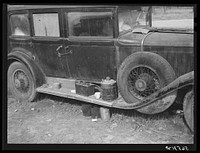 [Untitled photo, possibly related to: Close-up of car from Mississippi used for sleeping as well as shelter and traveling. Evidences of cooking outside are beside it. On highway near Camp Livingston. Alexandria, Louisiana]. Sourced from the Library of Congress.