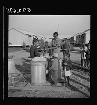Washing greens by pump near metal shelters at Okeechobee migratory labor camp. Belle Glade, Florida. Sourced from the Library of Congress.