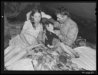 [Untitled photo, possibly related to: Construction worker with wife and neighbor's child in tent home near Alexandria, Louisiana. Ten men, two women, and two children live here]. Sourced from the Library of Congress.