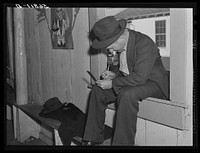 Fur buyer figuring out his bid on the next lot of muskrat pelts. The auction sale is held in a dance hall on Delacroix Island, Saint Bernard Parish, Louisiana. Sourced from the Library of Congress.