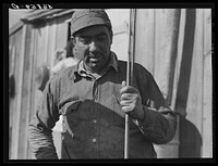 Spanish muskrat trapper by his marsh camp with reed in his hand. These reeds are used to mark location of traps. Delacroix Island, Saint Bernard Parish, Louisiana. Sourced from the Library of Congress.