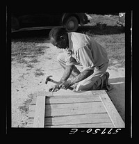 Assembling a joint of screen door. Screen door stock used is one inch by four inches.  Joints are cut square and held together with corrugated fasteners. Screening demonstration. Saint Mary's County, Ridge, Maryland. Sourced from the Library of Congress.