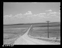 Road with Homestead, Montana, and grain elevators on the horizon. Sourced from the Library of Congress.