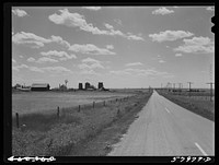 Highway, showing grain elevators and part of town of Froid, Montana. Sourced from the Library of Congress.