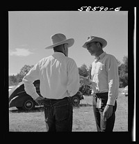 Lyman Brewster from Quarter Circle U Ranch in Birney, Montana, talking to a neighbor stockman at stockmen's picnic and barbecue. Spear's Siding, Wyola, Montana. Sourced from the Library of Congress.