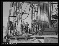 "Making a trip," pulling up old pipe to change bit on drilling pipe on the bottom of oil well at C.C. Graber pool of Continental oil company. Moundridge area near McPherson, Kansas. Sourced from the Library of Congress.