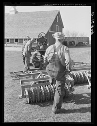 Fred Coulter, Iowa corn farmer, watching hired men adjust harrow onto tractor. Grundy County, Iowa. Sourced from the Library of Congress.