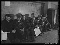 German-Russian farmers waiting to vote in presidential election, November 1940. Beaver Creek precinct, McIntosh County, North Dakota. Men with caps, sitting indoors. Sourced from the Library of Congress.