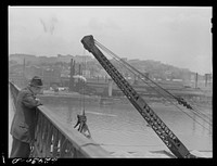 Man watching steamshovel unload sand from barges. Pittsburgh, Pennsylvania. Sourced from the Library of Congress.