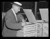 Commission merchant examining produce at terminal warehouse before auction begins. Chicago, Illinois. Sourced from the Library of Congress.