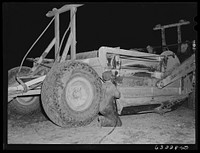 Member of road construction gang greasing "cats" at night. Grant County, Wisconsin. Sourced from the Library of Congress.