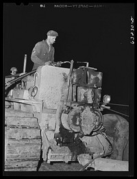 [Untitled photo, possibly related to: Member of road construction gang greasing "cats" at night. Grant County, Wisconsin]. Sourced from the Library of Congress.