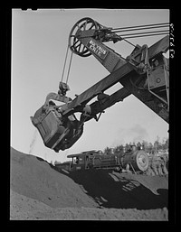 Electric shovel loading iron ore into railroad cars, eight cubic yards per shovelful. Mahoning Mine. Hibbing, Minnesota. Sourced from the Library of Congress.